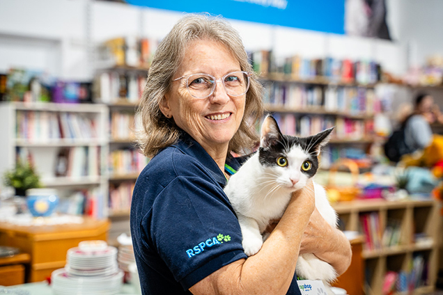 RSPCA Op Shop volunteer holding a black and white cat.